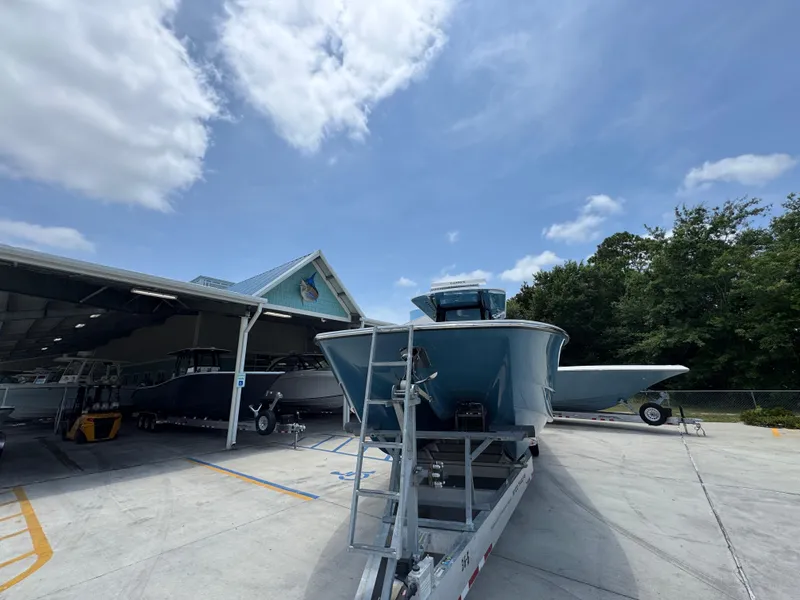 Slide: The Image of 2026 Invincible 36 Catamaran on trailer, parked outside a boat storage facility under a clear sky. - 6