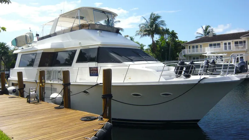 Slide: The Image of 1990 Viking Cockpit Motor Yacht docked by waterfront homes, under clear blue sky. - 1