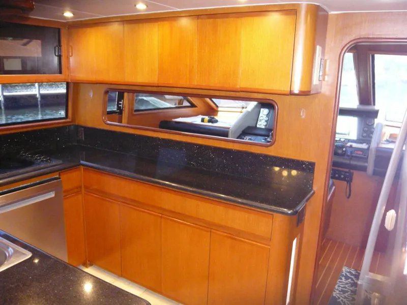 Slide: The Image of Interior of 1990 Viking Cockpit Motor Yacht with wooden cabinetry and black countertops. - 11