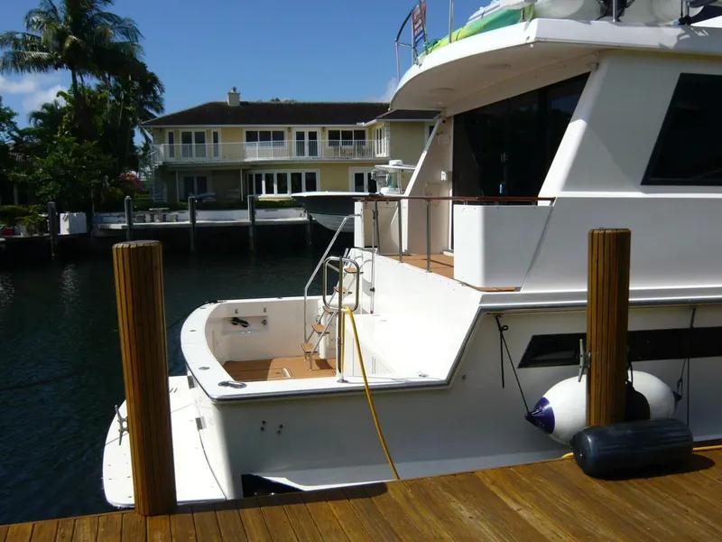 Slide: The Image of 1990 Viking Cockpit Motor Yacht docked near waterfront home, sunny day. - 2