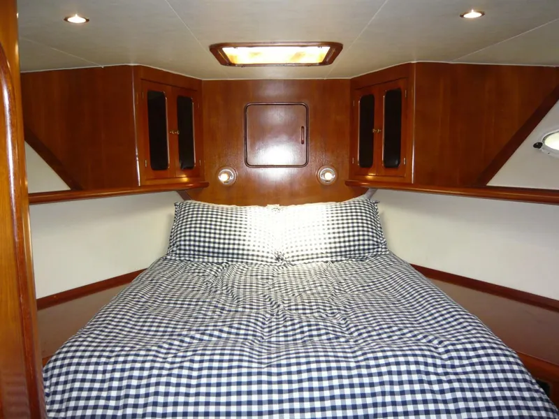 Slide: The Image of 1990 Viking Cockpit Motor Yacht bedroom with checkered bedding and wooden cabinetry. - 20