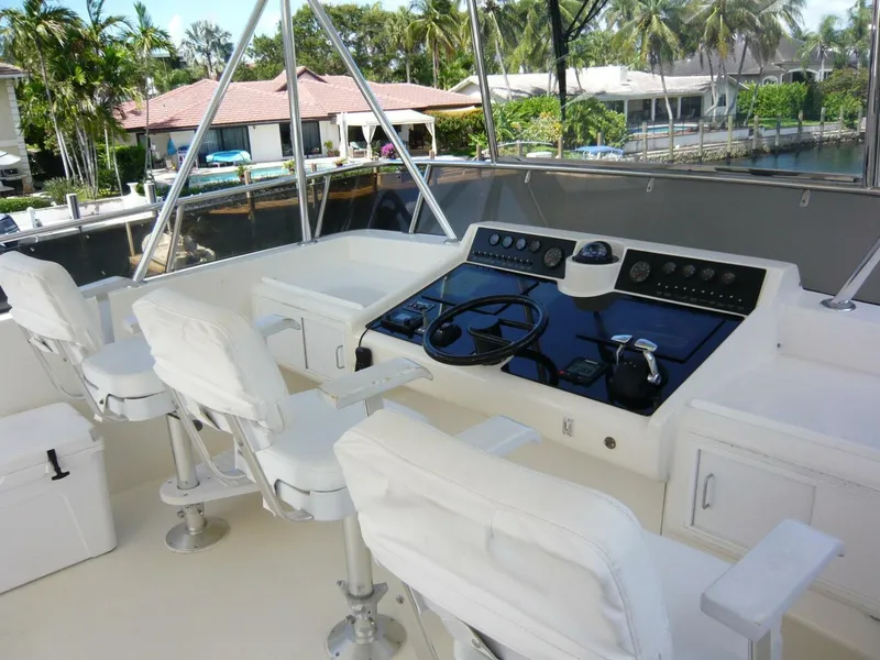 Slide: The Image of 1990 Viking Cockpit Motor Yacht helm with white seating and control panel. - 34