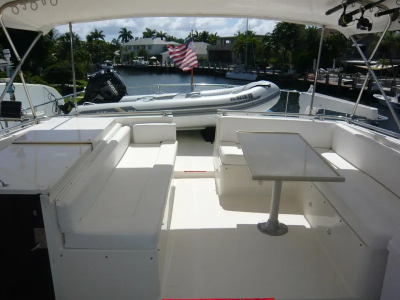 Slide: The Image of 1990 Viking Cockpit Motor Yacht with seating area and table, docked with inflatable boat nearby. - 36
