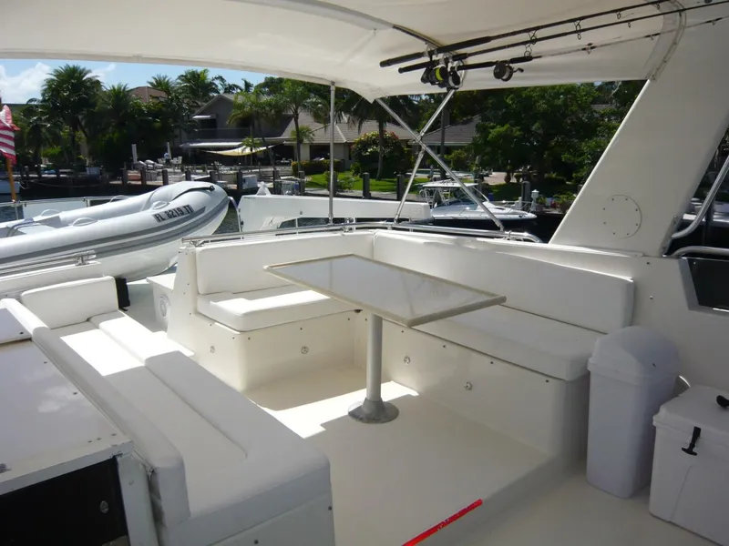 Slide: The Image of 1990 Viking Cockpit Motor Yacht with spacious seating and table, docked near palm trees. - 37