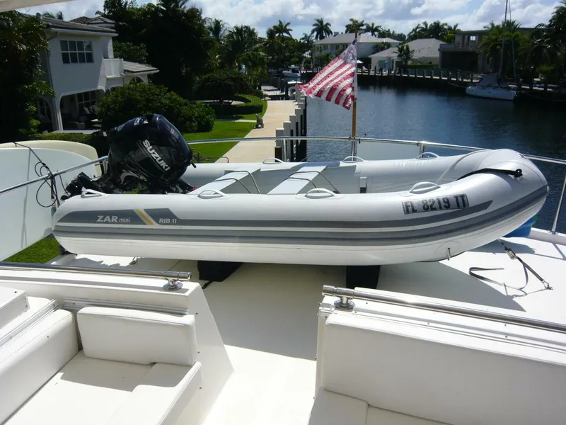 Slide: The Image of Inflatable boat on 1990 Viking Cockpit Motor Yacht with Suzuki outboard motor, docked by waterfront homes. - 39