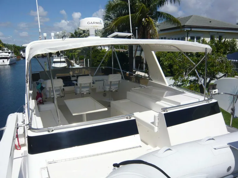 Slide: The Image of 1990 Viking Cockpit Motor Yacht with spacious seating and canopy, docked near palm trees. - 41