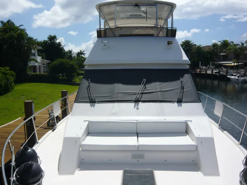 Slide: The Image of 1990 Viking Cockpit Motor Yacht with spacious deck seating, docked by lush greenery and waterfront homes. - 44