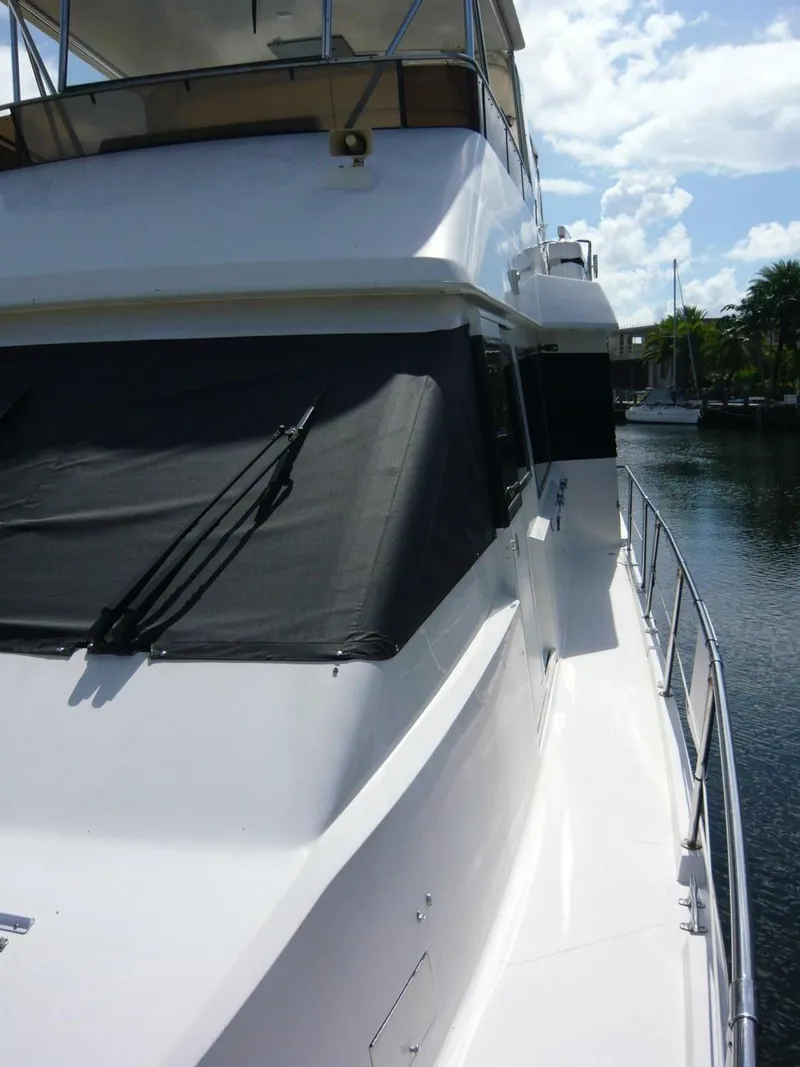 Slide: The Image of 1990 Viking Cockpit Motor Yacht docked, featuring sleek white exterior and shaded windows. - 45