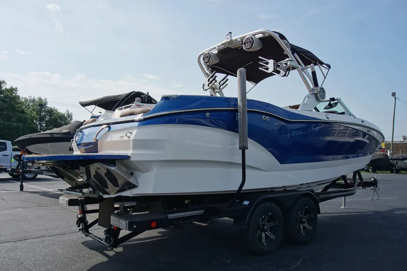 Slide: The Image of 2019 MasterCraft X24 boat on trailer, blue and white design, parked outdoors. - 5