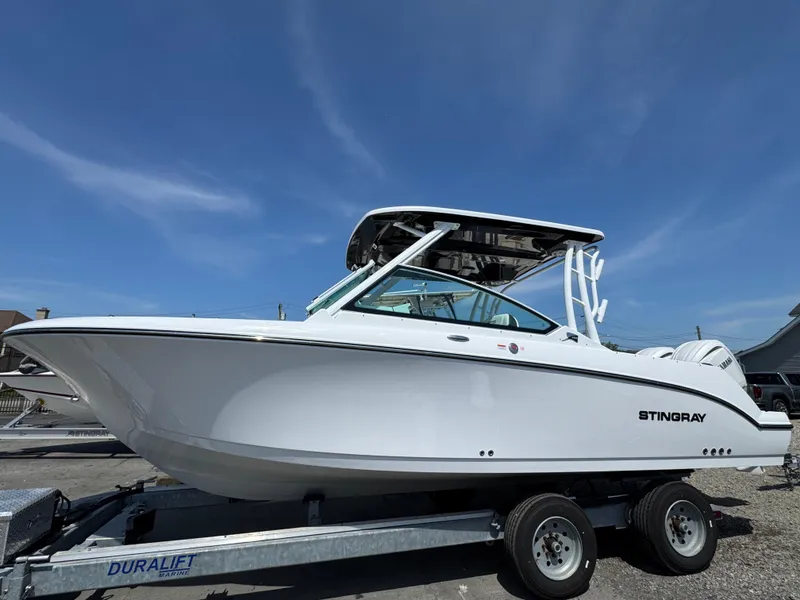 Slide: The Image of 2025 Stingray 259 DC boat on trailer under clear blue sky. - 1