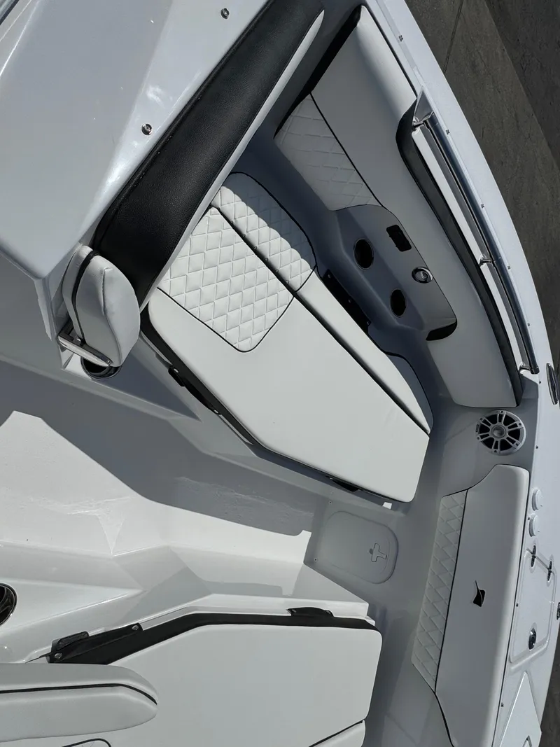 Slide: The Image of 2025 Stingray 259 DC boat interior with white quilted seating and cup holders. - 10