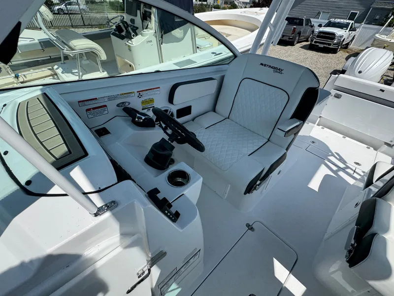 Slide: The Image of 2025 Stingray 259 DC boat interior with white seating and steering console. - 14