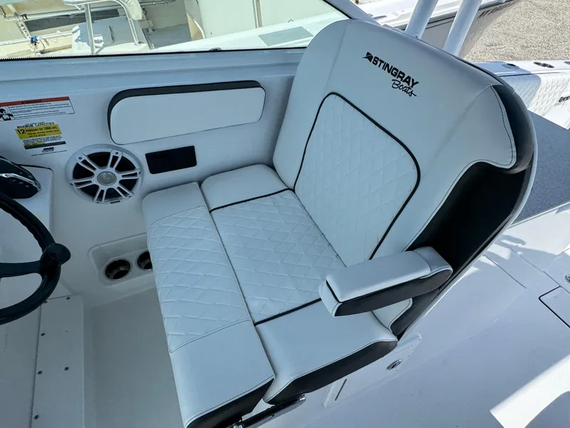 Slide: The Image of 2025 Stingray 259 DC boat seat with white quilted upholstery and armrest. - 6