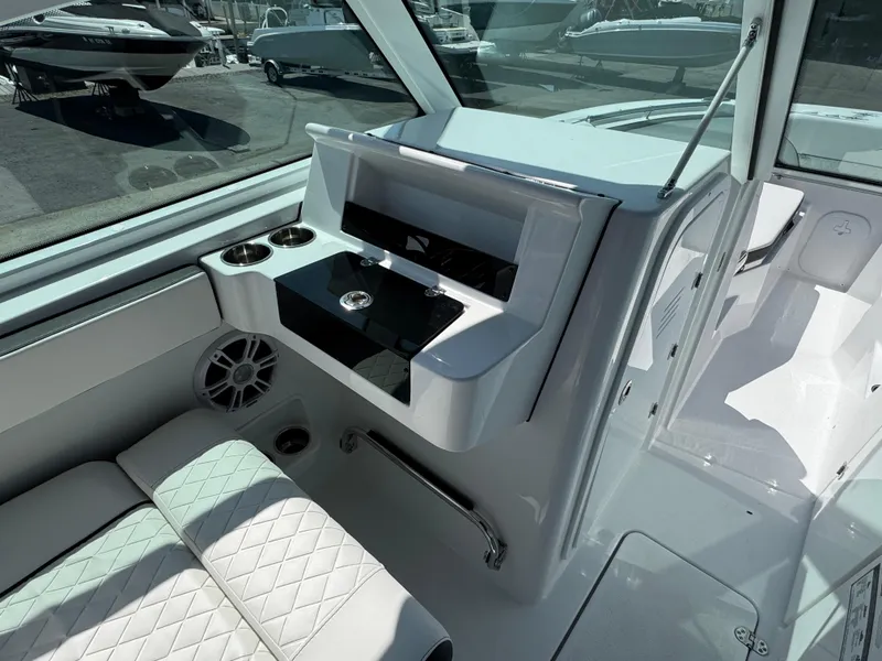 Slide: The Image of 2025 Stingray 259 DC boat interior with seating, cup holders, and storage compartment. - 9