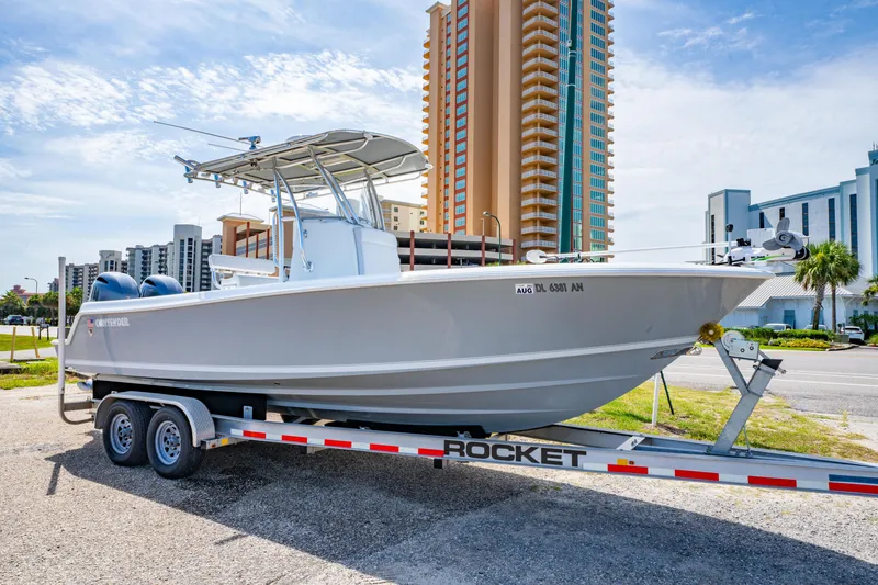 The Image of 2022 Contender 25T boat on trailer, urban background, clear sky. - 0