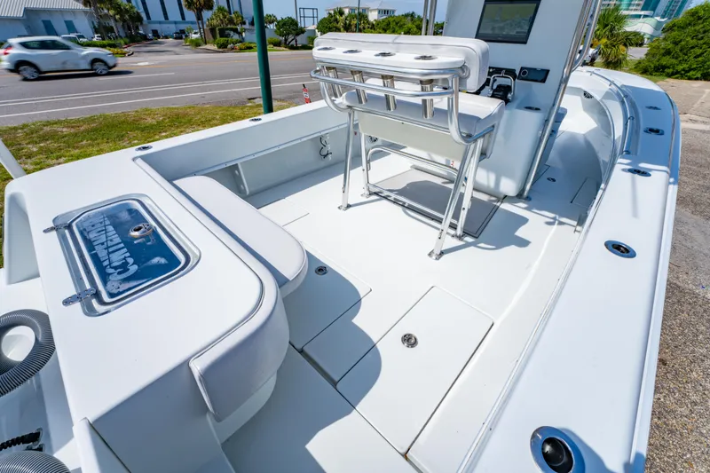 Slide: The Image of 2022 Contender 25T boat interior with seating and console, parked near a road. - 19