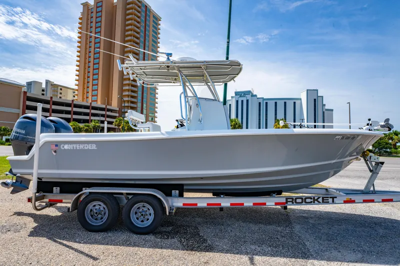 Slide: The Image of 2022 Contender 25T boat on trailer, parked near tall buildings under a clear sky. - 2