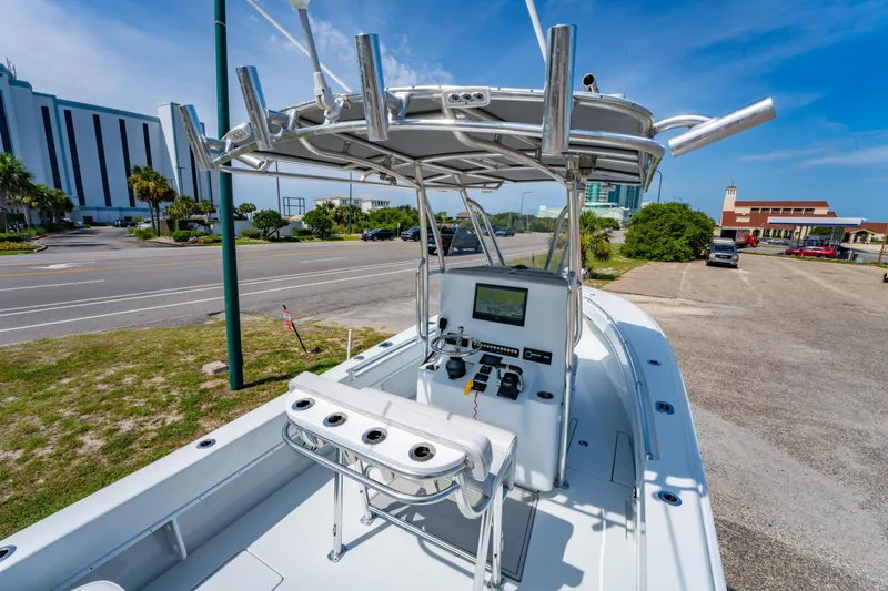 Slide: The Image of 2022 Contender 25T boat with console and rod holders, parked near a road under a clear sky. - 20