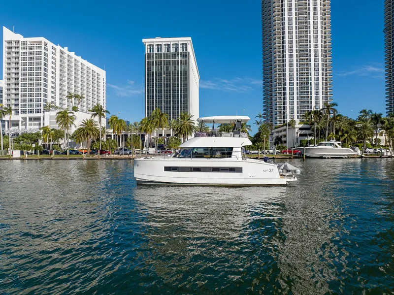 Slide: The Image of 2017 Fountaine Pajot MY 37 yacht on water, with city skyline and palm trees in background. - 1