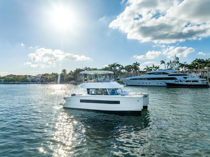 Slide: The Image of 2017 Fountaine Pajot MY 37 yacht on sunny water, with palm trees and boats in the background. - 3