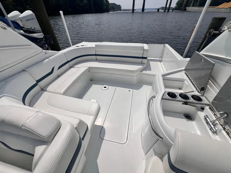Slide: The Image of 2005 Formula 330 Sun Sport boat interior with white seating and cup holders by the water. - 12