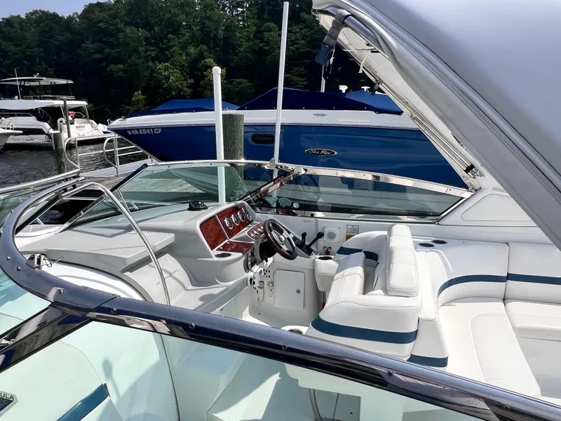 Slide: The Image of 2005 Formula 330 Sun Sport boat interior with white seating and dashboard, docked near other boats. - 26