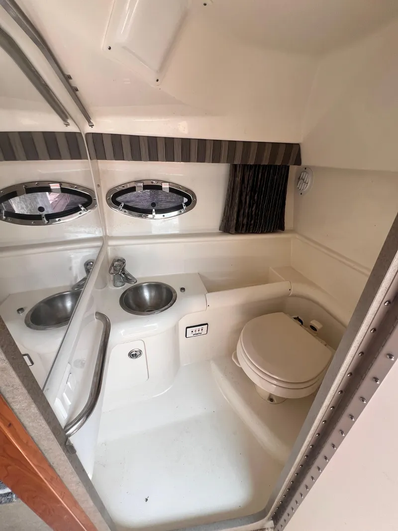 Slide: The Image of 2005 Formula 330 Sun Sport boat bathroom with sink, toilet, and porthole windows. - 33