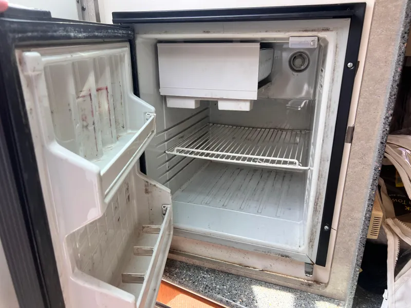 Slide: The Image of Open mini fridge inside a 2005 Formula 330 Sun Sport boat, showing empty shelves. - 44