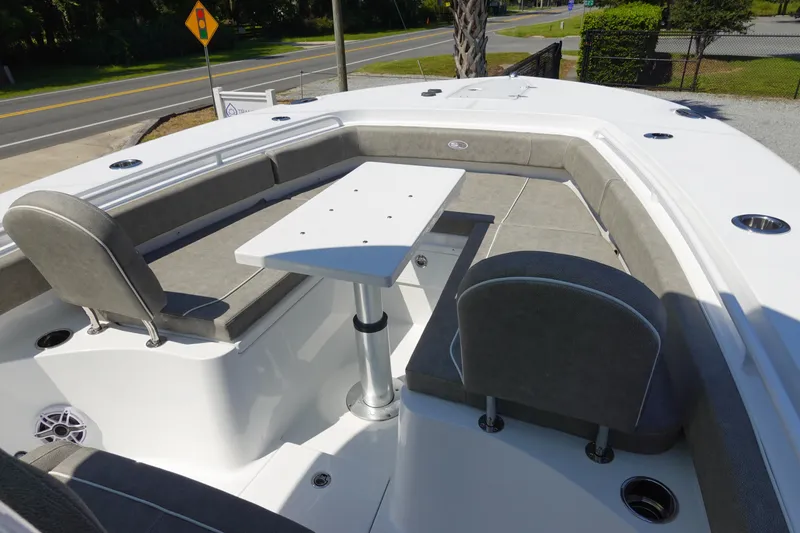 Slide: The Image of 2026 Sea Hunt Gamefish 27 boat interior with seating and table, docked near a road. - 26