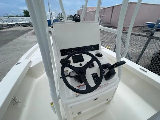 Slide: The Image of 2025 Pathfinder 2200 TRS boat console with steering wheel and controls, docked outdoors. - 12