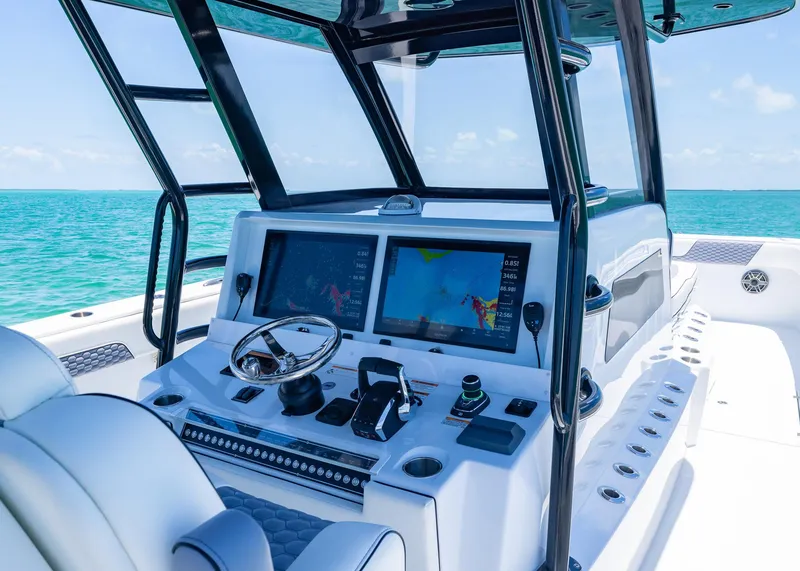 Slide: The Image of 2026 Invincible 38 Catamaran helm with dual screens, steering wheel, and ocean view. - 27