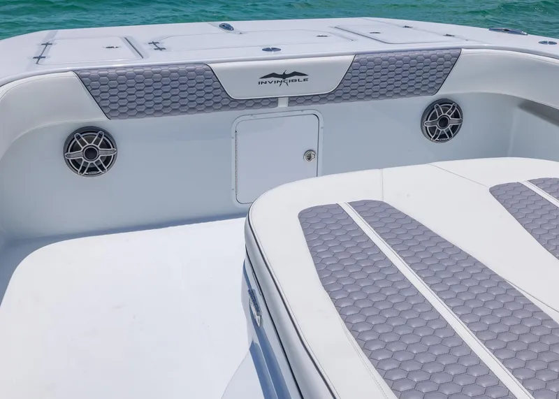 Slide: The Image of 2026 Invincible 38 Catamaran interior with gray seating and speakers, on turquoise water. - 4