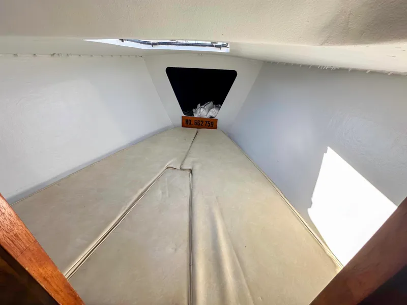 Slide: The Image of Interior view of a 1983 Racing Sloop sailboat cabin with beige cushions. - 13