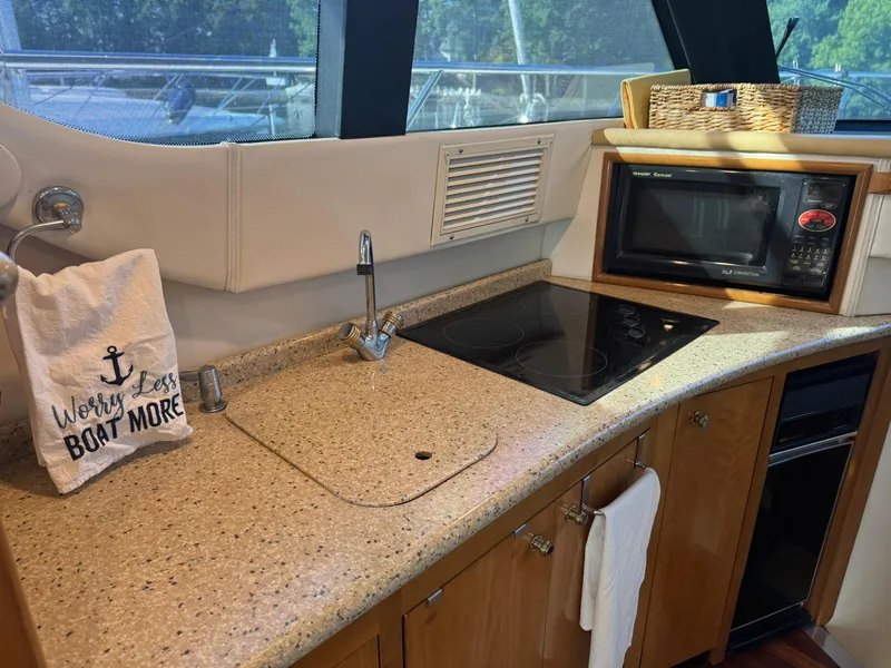Slide: The Image of 2001 Carver 450 Voyager Pilothouse kitchen with stove, microwave, and "Worry Less, Boat More" towel. - 31