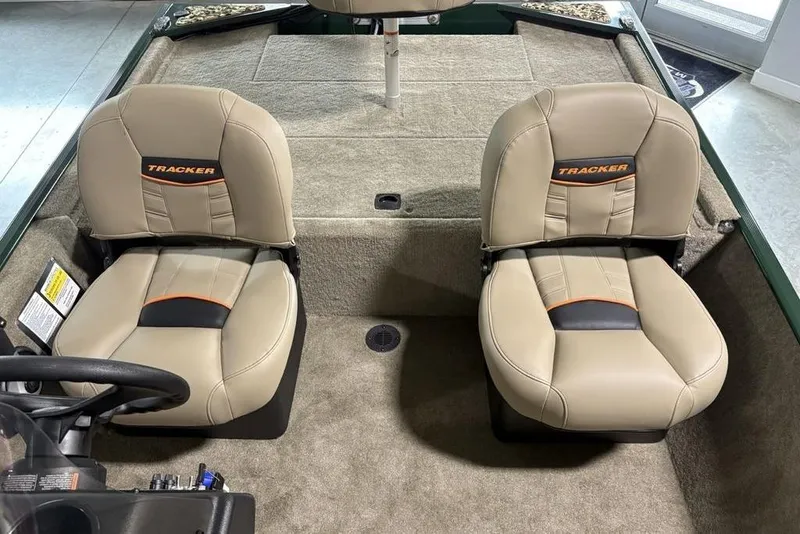 Slide: The Image of 2026 Tracker Bass Tracker® Classic Limited boat seats, beige with orange accents, in a carpeted interior. - 11