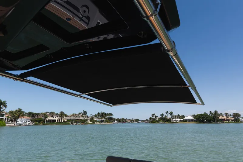 Slide: The Image of Pardo Yachts 38 (2025) with sunshade, overlooking serene waterfront and luxury homes. - 30