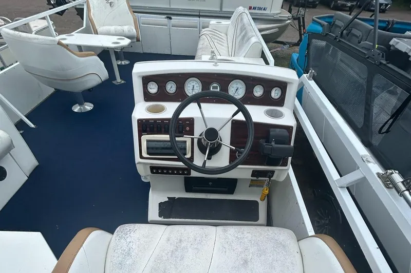 Slide: The Image of Interior of a 1996 JC Suntoon 24 boat with white seating and control panel. - 11