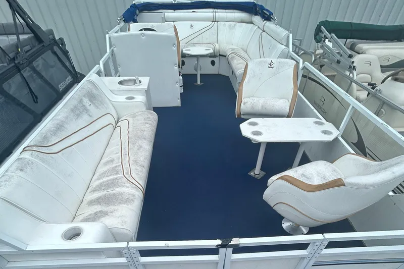 Slide: The Image of 1996 JC Suntoon 24 boat interior with white seating and blue flooring. - 8