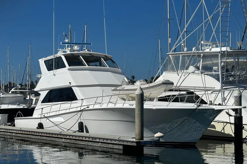The Image of 2000 Viking Enclosed Flybridge yacht docked at marina under clear blue sky. - 0