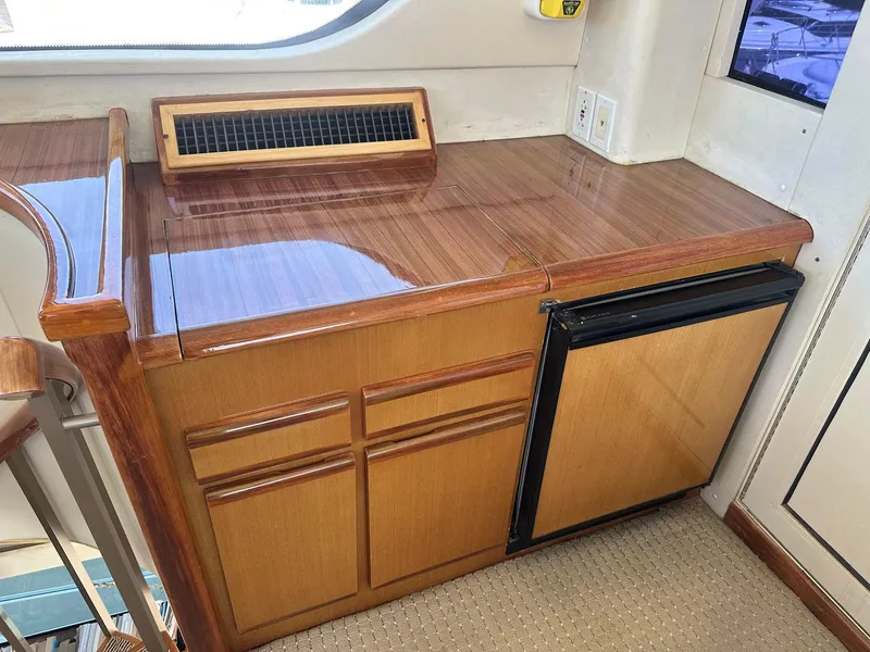 Slide: The Image of Wooden cabinetry and mini fridge inside 2000 Viking Enclosed Flybridge yacht interior. - 22