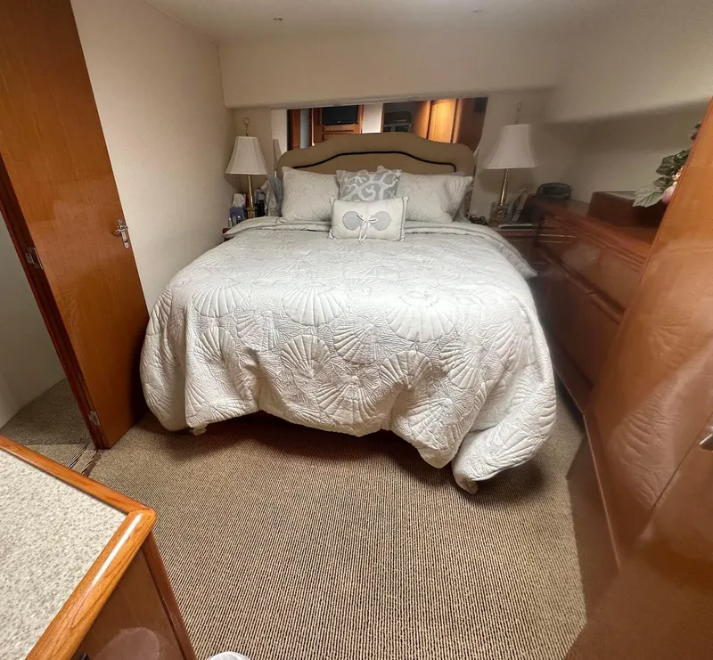 Slide: The Image of Cozy bedroom in 2000 Viking Enclosed Flybridge yacht with elegant bedding and wooden furnishings. - 28