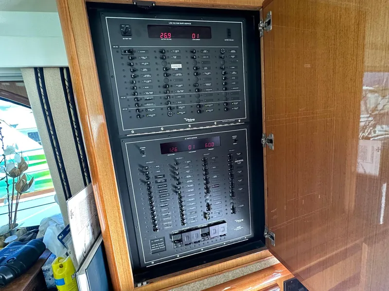 Slide: The Image of Electrical panel inside a 2000 Viking Enclosed Flybridge yacht, showcasing control switches and displays. - 32