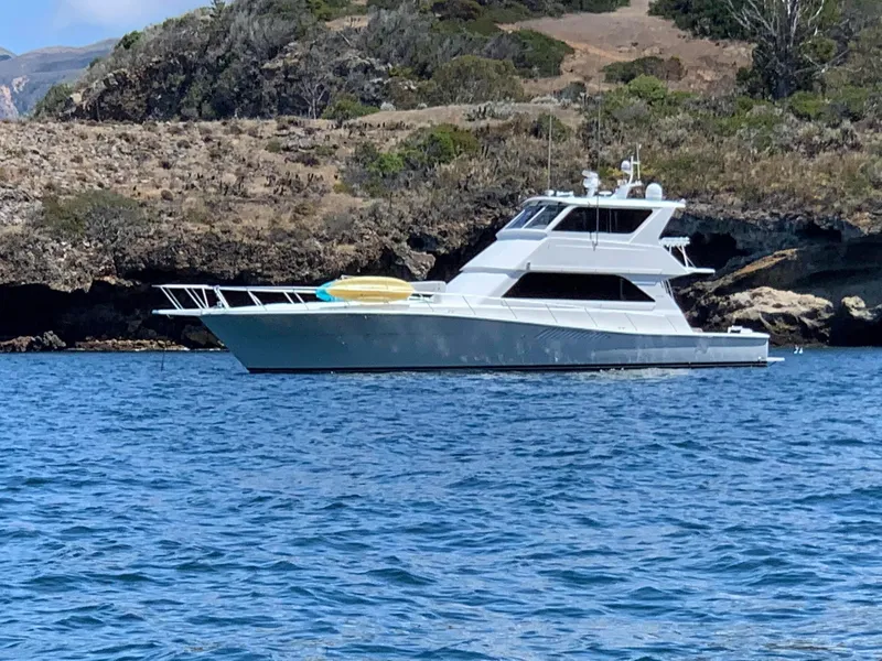 Slide: The Image of 2000 Viking Enclosed Flybridge yacht on calm water near rocky shoreline. - 5