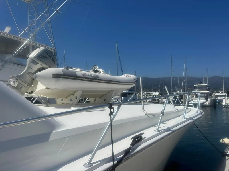 Slide: The Image of 2000 Viking Enclosed Flybridge yacht with dinghy, docked in a marina under clear blue skies. - 7