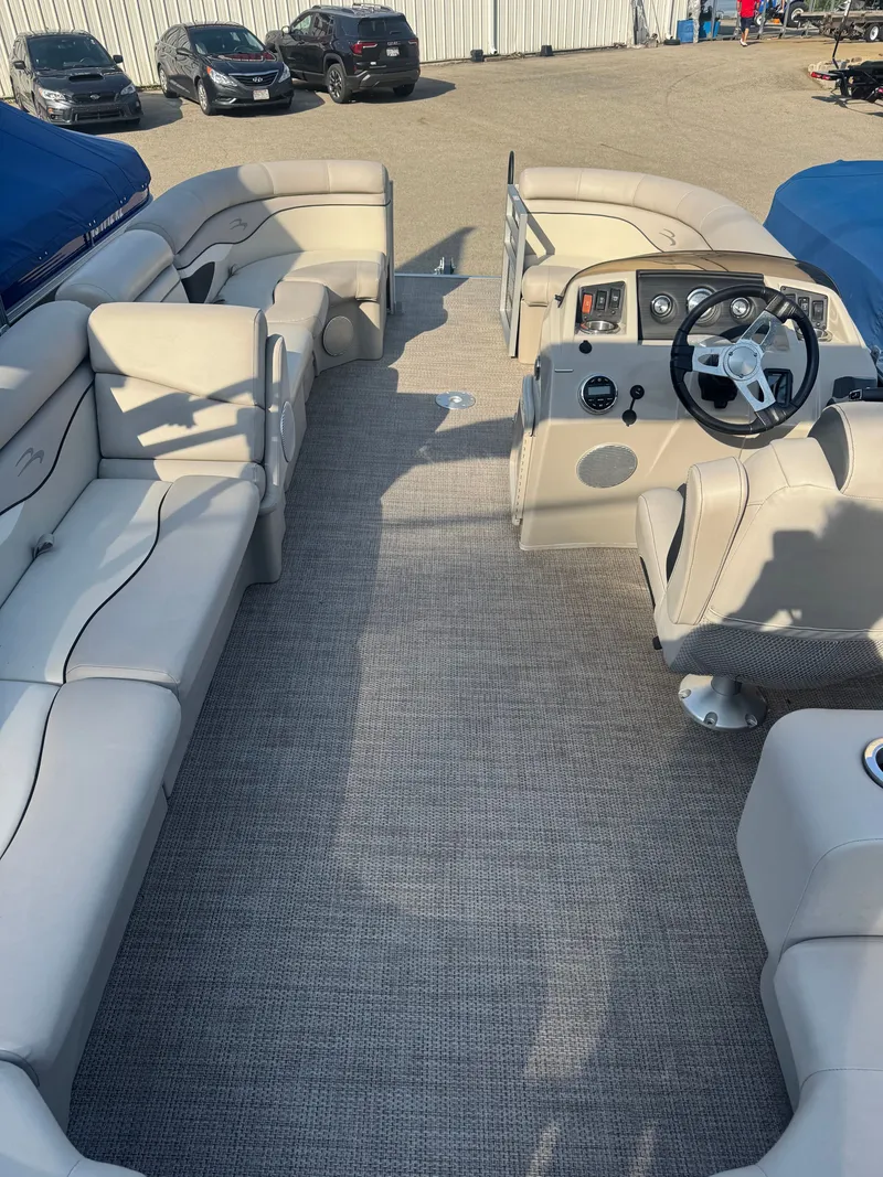 Slide: The Image of The image shows the interior of a Bennington 20SSRCX pontoon boat with beige seating and a helm. - 18