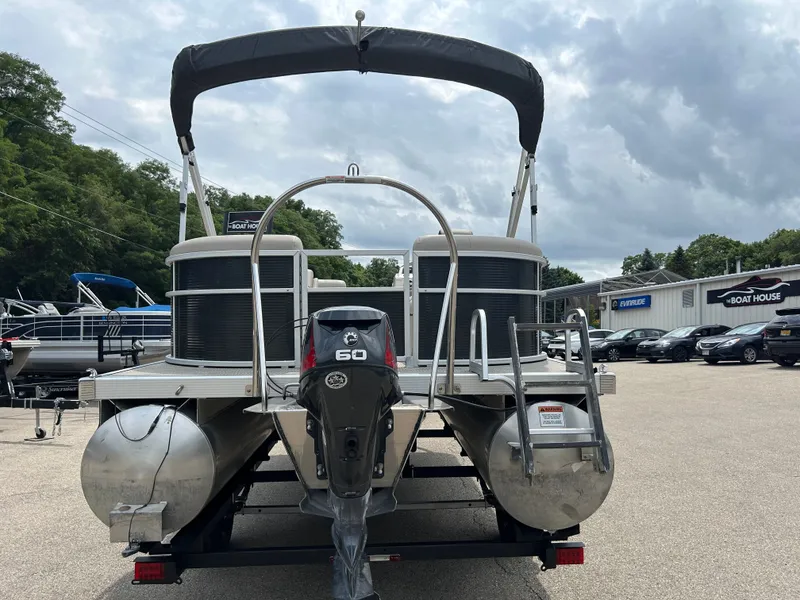 Slide: The Image of A 2019 Bennington pontoon boat with a 60 HP motor, parked on a trailer. - 14