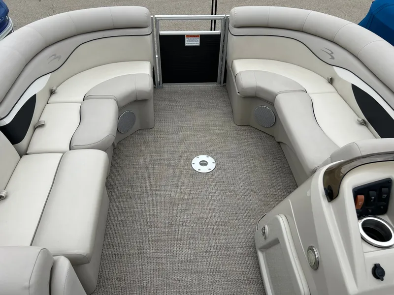 Slide: The Image of Interior of a Bennington 20SSRCX pontoon boat with beige upholstered seating and helm console. - 20