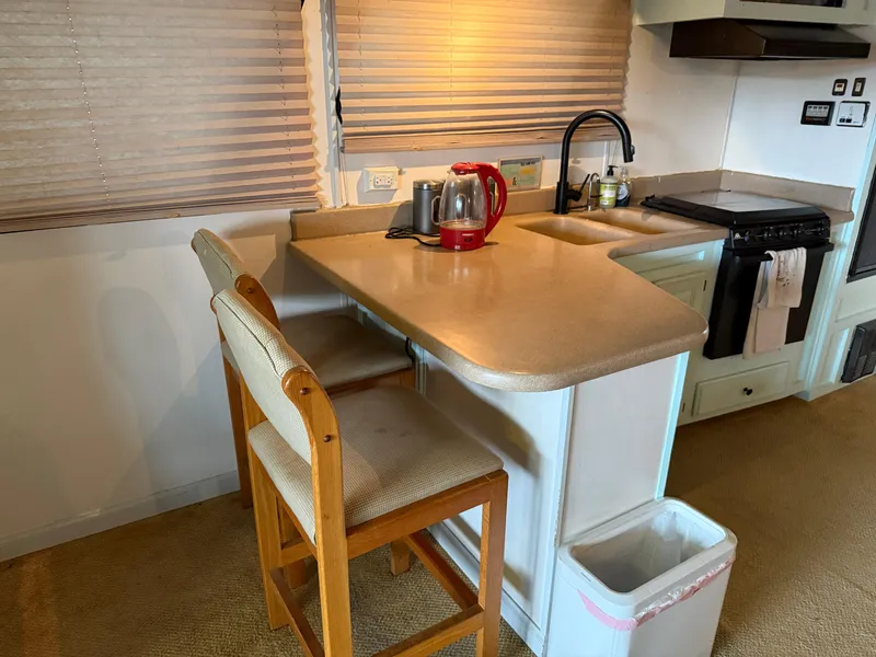 Slide: The Image of Compact kitchen area in a 2001 Myacht M Yacht with counter, chairs, and appliances. - 21