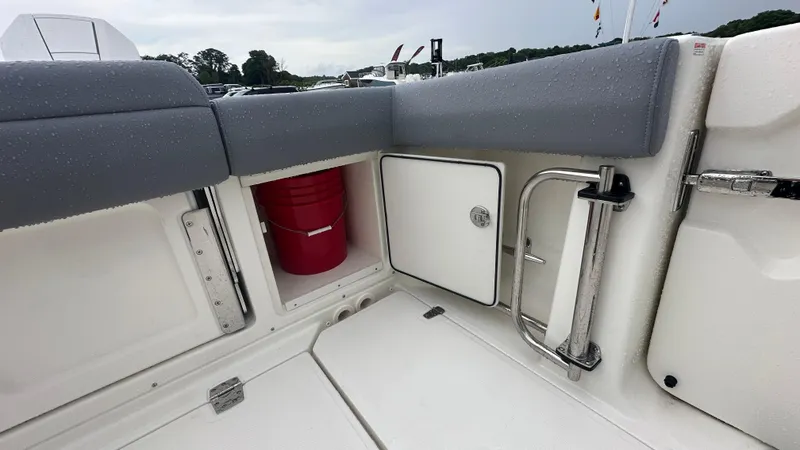 Slide: The Image of 2025 Boston Whaler 330 Outrage boat interior with storage compartment and red bucket. - 10