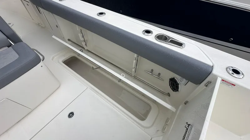 Slide: The Image of 2025 Boston Whaler 330 Outrage interior storage compartment and seating area. - 12